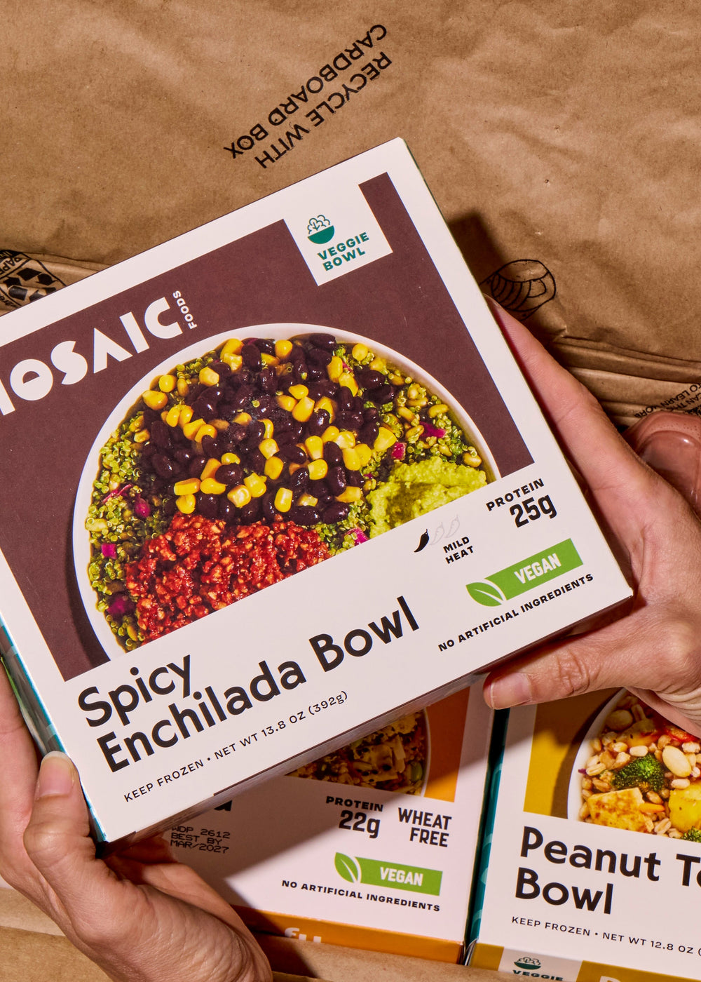Mosaic Foods brand food packaging held by a person with a cardboard box in the background
